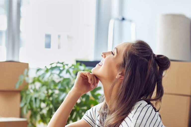 happy woman smiling in house with boxes in background